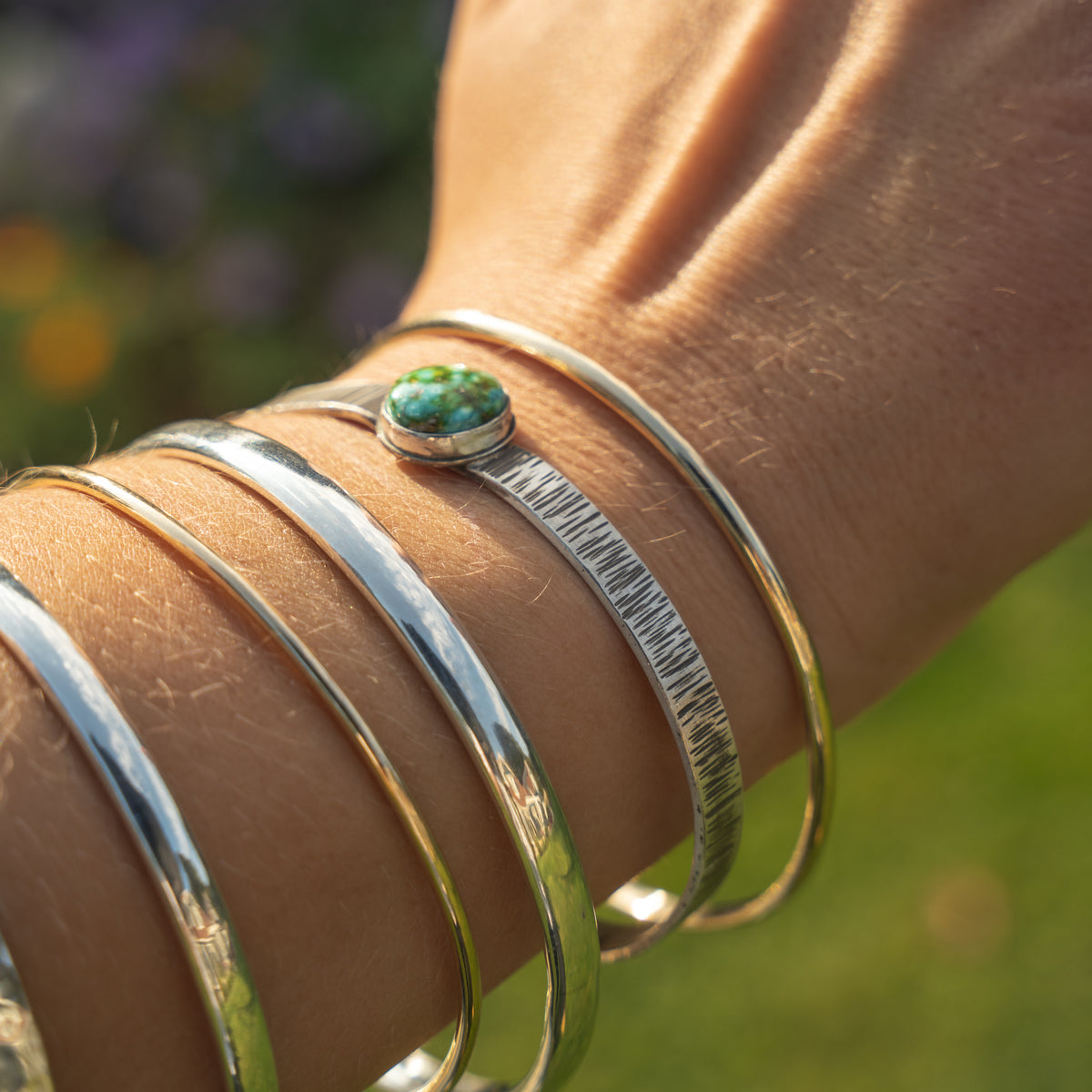 handmade sterling silver bangles in three thickness along with silver cuffs set with turquoise.  Made in the Uk by Laura De Zordo Jewellery  Edit alt text